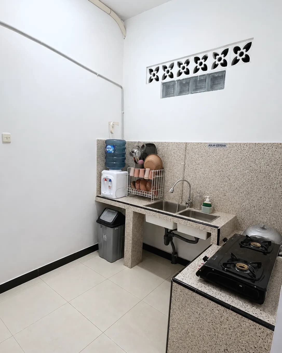 Dapur lantai bawah Kos Mbak Elis dengan kompor gas, wastafel, rak piring, dan dispenser galon
