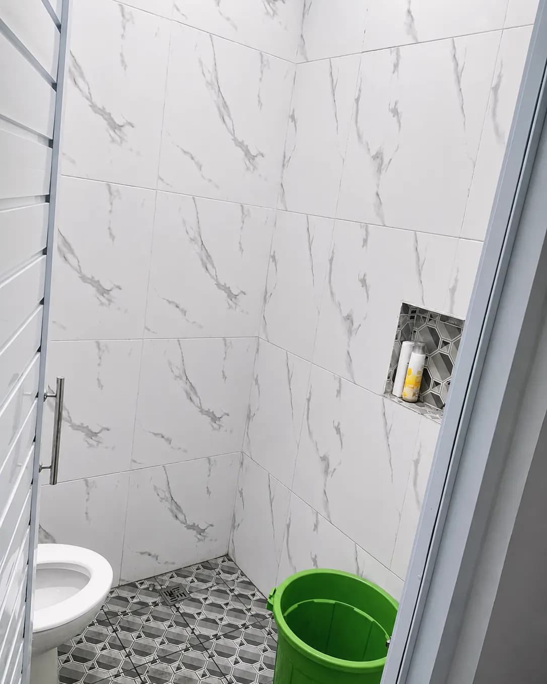 Kamar mandi bersama dengan kloset duduk dan shower di Kos Mbak Elis, Sleman