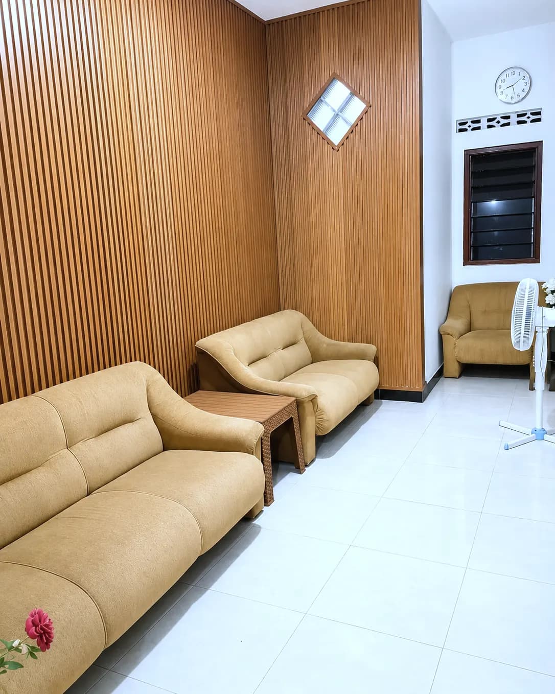 Ruang tamu Kos Mbak Elis dengan dua sofa dan dinding kayu bersirip